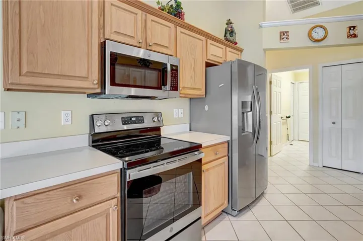 Kitchen featuring light countertops, light brown cabinets, appliances with stainless steel finishes, and visible vents