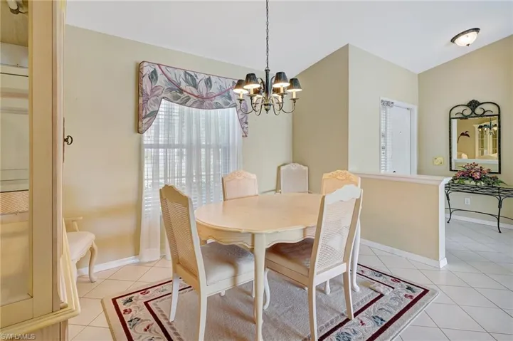 Dining room featuring baseboards, lofted ceiling, a chandelier, and light tile patterned floors