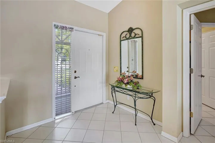 Foyer entrance with light tile patterned flooring and baseboards