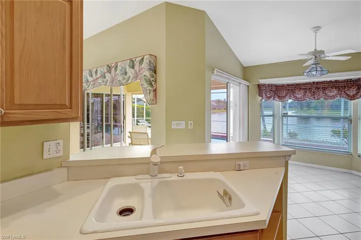 Kitchen with light countertops, a sink, a ceiling fan, lofted ceiling, and light tile patterned floors
