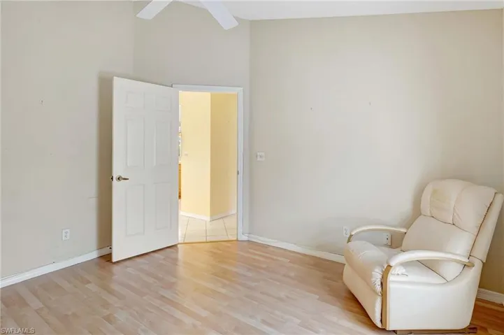 Sitting room featuring baseboards, light wood-type flooring, ceiling fan, and vaulted ceiling