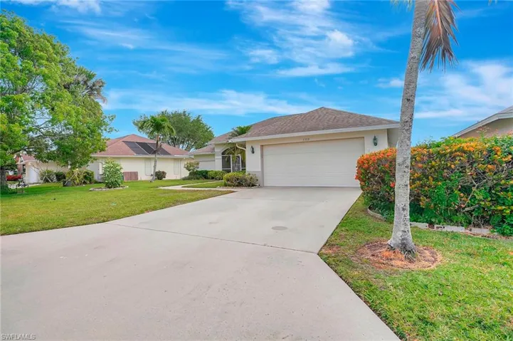 Ranch-style home with concrete driveway, stucco siding, an attached garage, and a front lawn