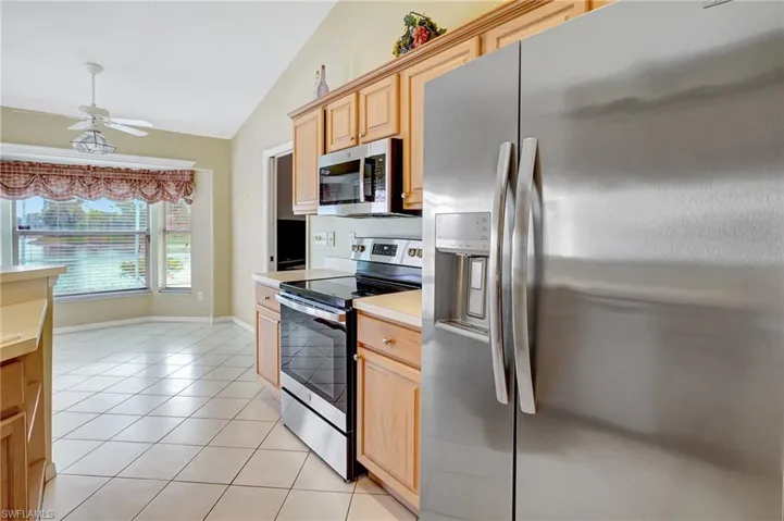 Kitchen with light countertops, stainless steel appliances, a ceiling fan, vaulted ceiling, and light tile patterned floors