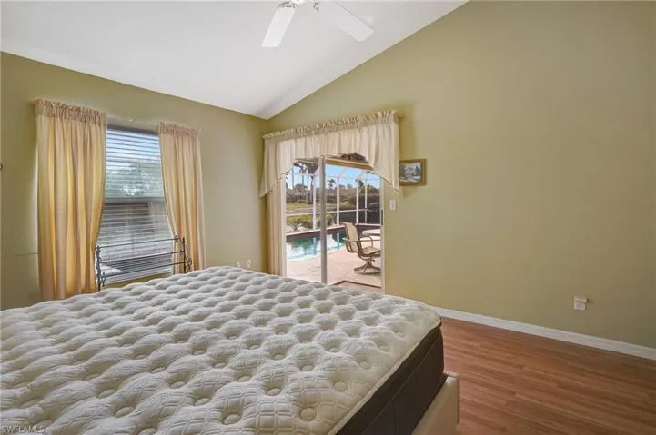 Bedroom featuring baseboards, wood finished floors, a ceiling fan, lofted ceiling, and access to exterior