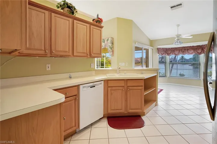 Kitchen featuring light countertops, a sink, a peninsula, white dishwasher, and light tile patterned floors