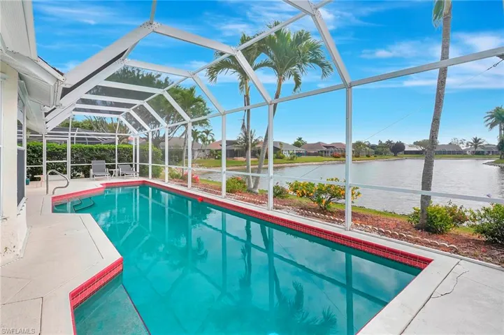 Pool featuring glass enclosure, a water view, and a patio
