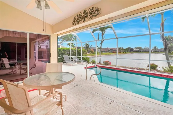 Outdoor pool with a patio, a water view, ceiling fan, and glass enclosure