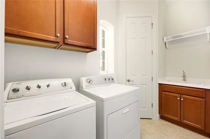 Laundry room with cabinet space, light tile patterned flooring, and washer and clothes dryer