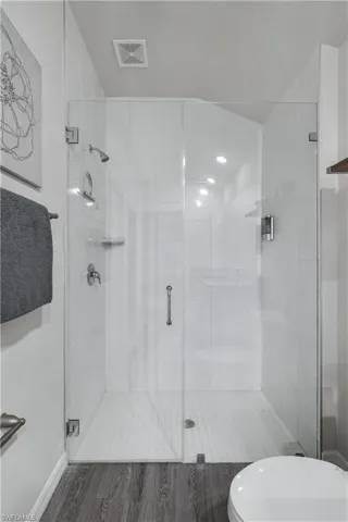 Full bath with a shower stall and wood finished floors