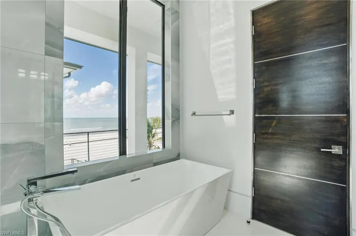 Bathroom with a freestanding tub and a water view Virtually Enhanced
