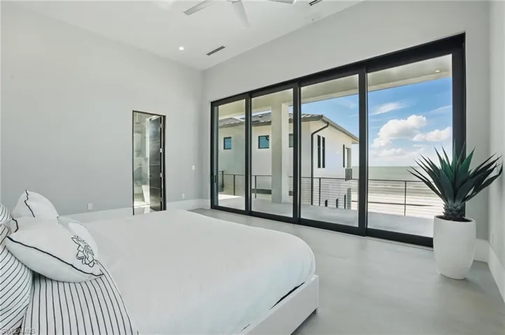 Bedroom featuring access to outside, concrete flooring, and ceiling fan Virtually Enhanced