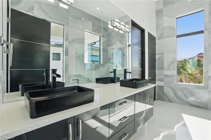 Bathroom with double vanity, a marble finish shower, and tile walls Virtually Enhanced
