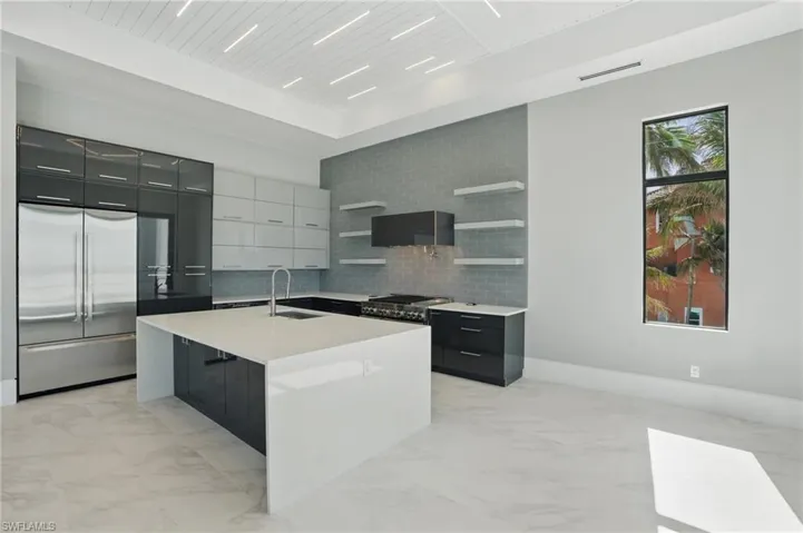 Two tone kitchen with modern cabinets, open shelves, stainless steel appliances, light marble finish floors, and dual tone cabinets Virtually Enhanced