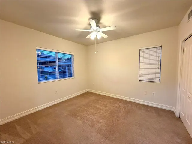 Carpeted spare room featuring baseboards and ceiling fan