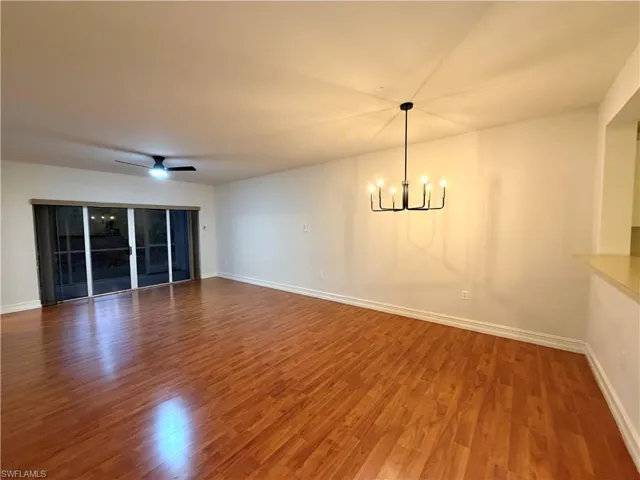 Unfurnished dining area featuring wood finished floors, a chandelier, and ceiling fan