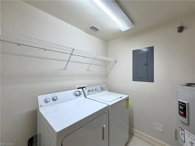 Laundry area featuring water heater, electric panel, and washing machine and dryer