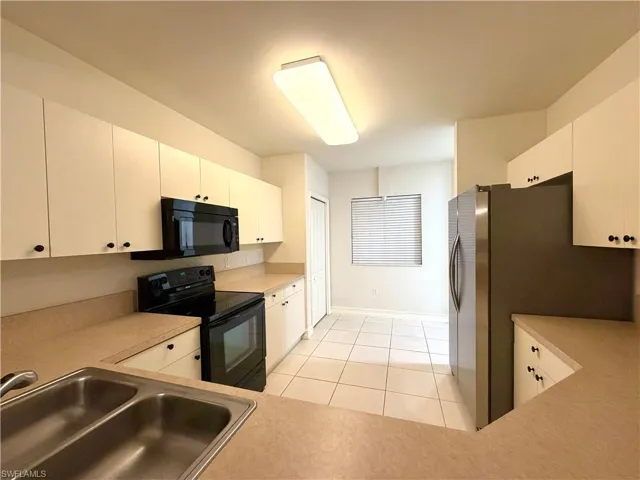 Kitchen with black appliances, light countertops, and white cabinets