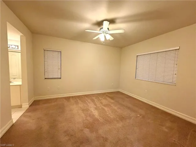 Unfurnished bedroom with light carpet, a ceiling fan, and ensuite bathroom
