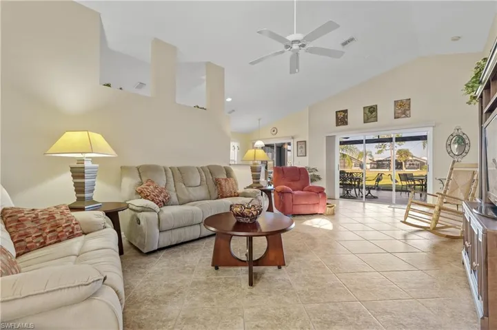 Tiled living room with ceiling fan and high vaulted ceiling