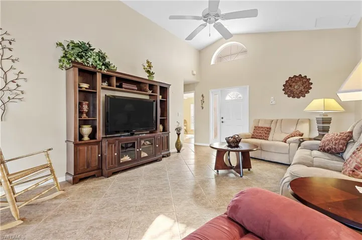 Tiled living room featuring ceiling fan and high vaulted ceiling