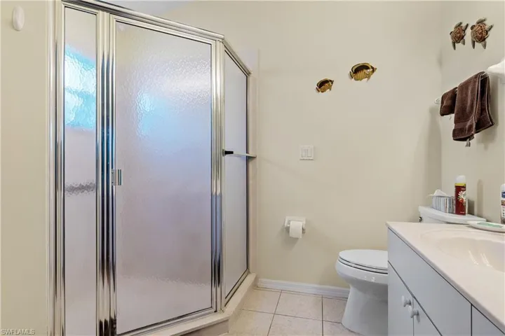 Bathroom featuring tile patterned flooring, vanity, a shower with shower door, and toilet