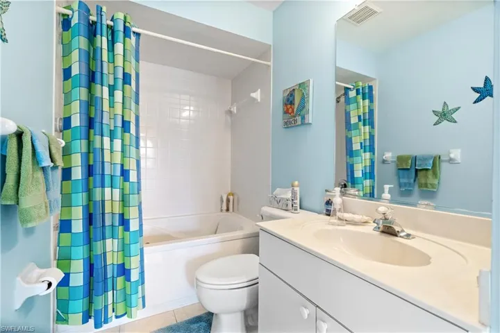 Full bathroom with tile patterned floors, shower / tub combo with curtain, vanity, and toilet