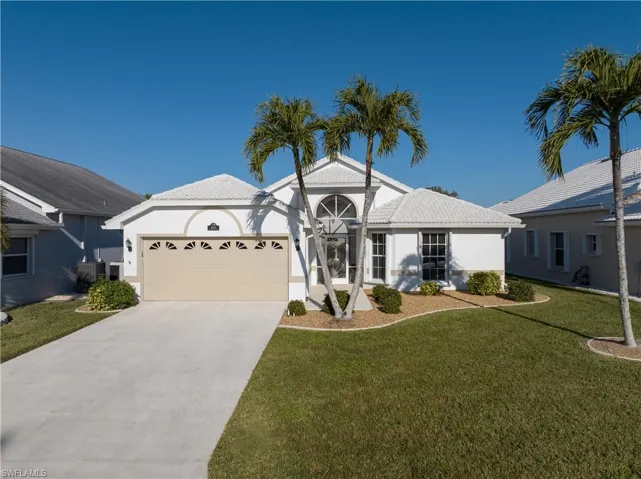 View of front of home featuring central AC unit, a garage, and a front lawn