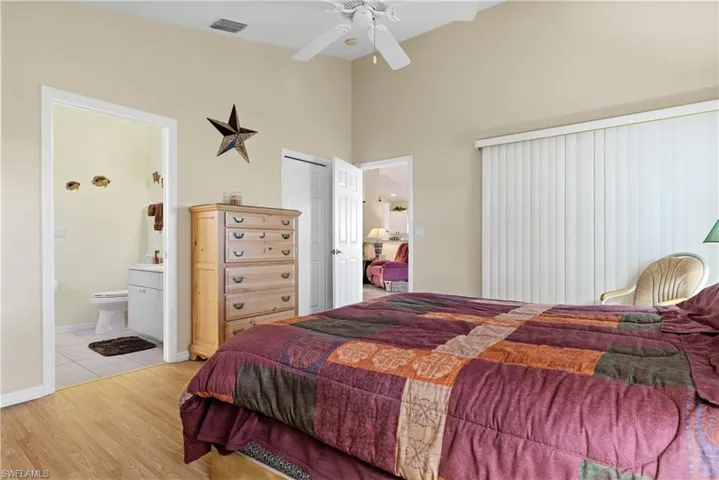 Bedroom featuring light wood-type flooring, a closet, ensuite bathroom, and ceiling fan
