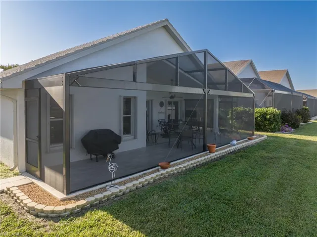 Back of property featuring a yard, glass enclosure, and a patio area