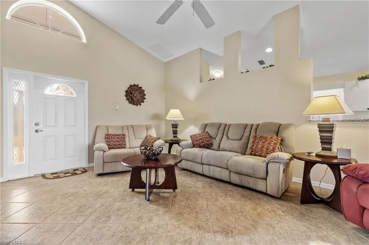 Living room with ceiling fan, light tile patterned floors, plenty of natural light, and high vaulted ceiling
