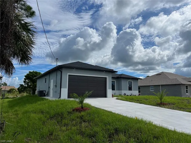 View of front facade with a front yard, a garage, and central AC unit