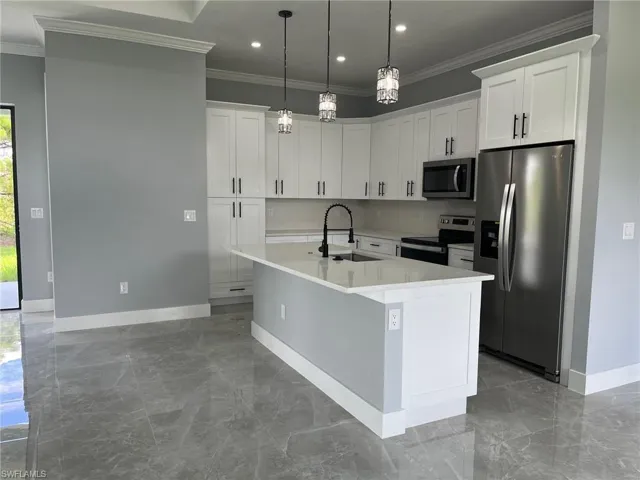 Kitchen featuring plenty of natural light, sink, appliances with stainless steel finishes, and a center island with sink