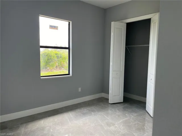 Unfurnished bedroom with a closet and light tile flooring