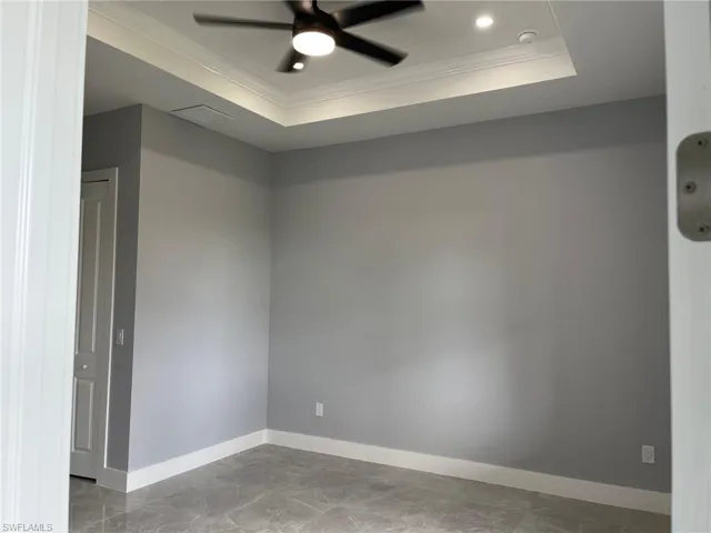 Unfurnished room featuring tile floors, ornamental molding, ceiling fan, and a raised ceiling