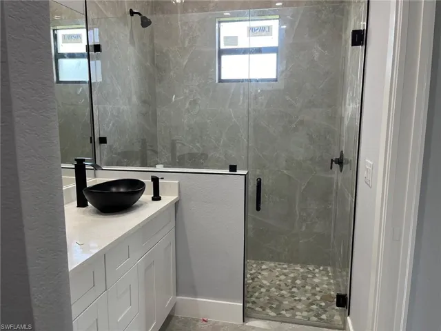 Bathroom with an enclosed shower, tile flooring, and vanity