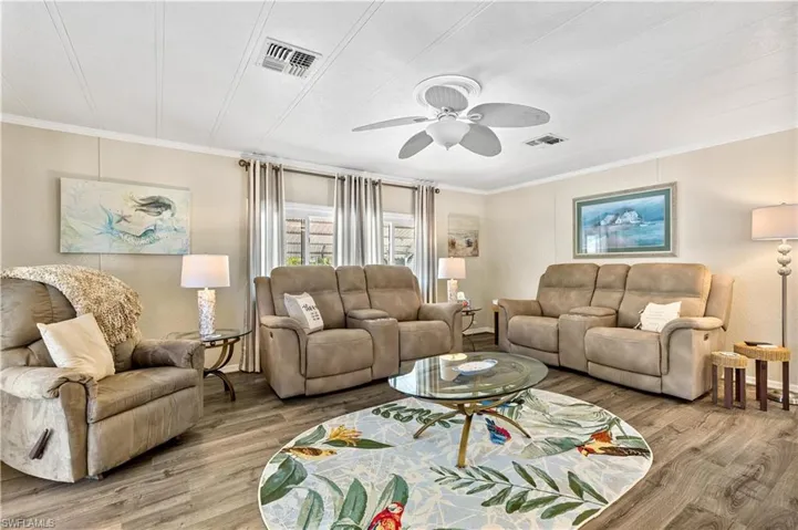 Living room with ceiling fan, ornamental molding, and hardwood / wood-style flooring
