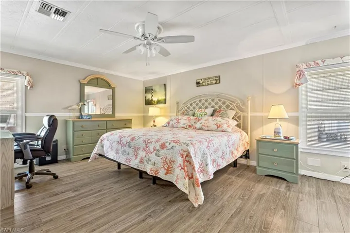 Bedroom with ceiling fan, multiple windows, hardwood / wood-style flooring, and ornamental molding