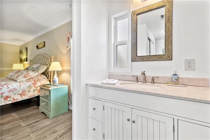 Bathroom featuring ornamental molding, vanity with extensive cabinet space, and wood-type flooring