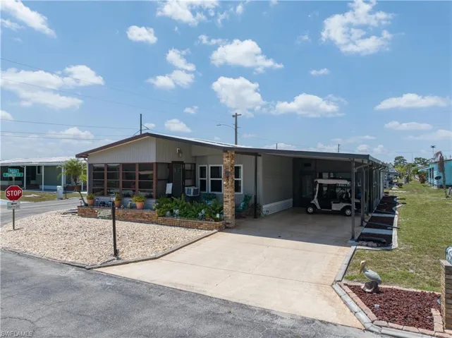 Manufactured / mobile home featuring a front yard and a carport