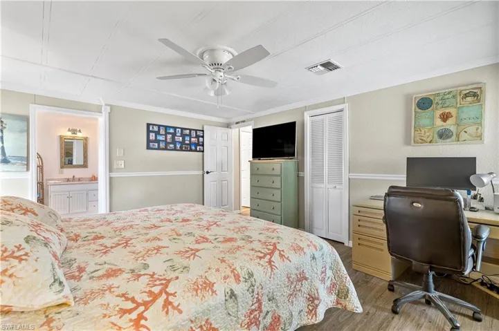 Bedroom with a closet, ceiling fan, hardwood / wood-style flooring, ornamental molding, and ensuite bath