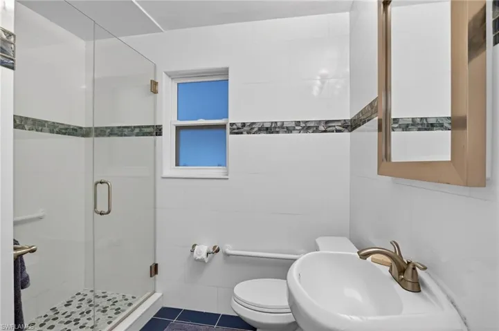 Full bathroom featuring a shower stall and full tile walls