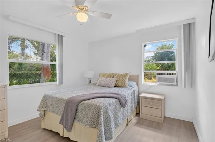 Bedroom 1 featuring light wood-type flooring, a ceiling fan, and multiple windows