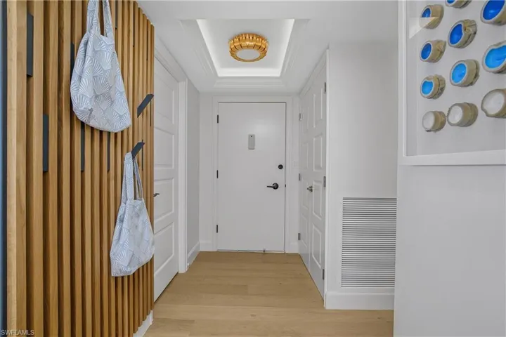 entry foyer with a raised ceiling, custom feature wall, and wood floors