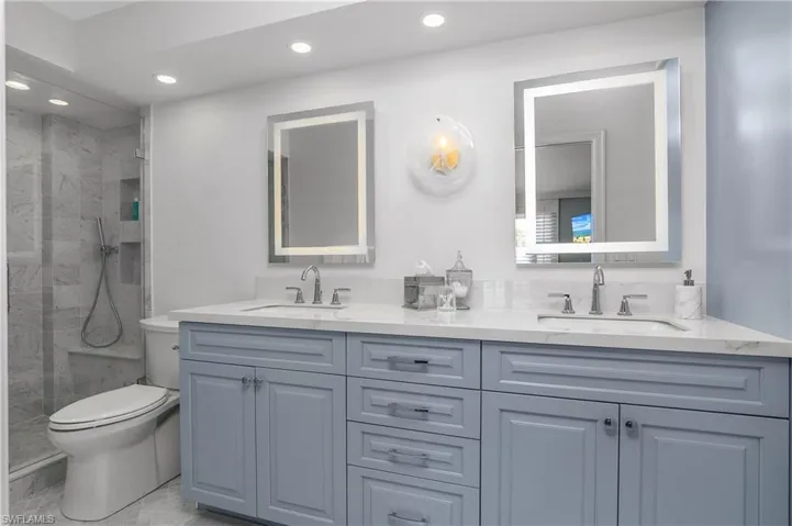 Full bathroom with double vanity, a marble finish shower, and recessed lighting