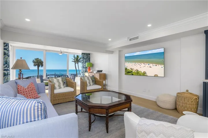 Living area featuring custom wood flooring, a water view, crown molding, and recessed lighting