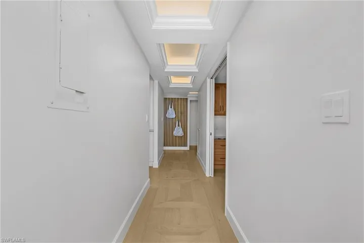 Hallway with beautiful custom floors, a lighted tray ceiling, and feature wall