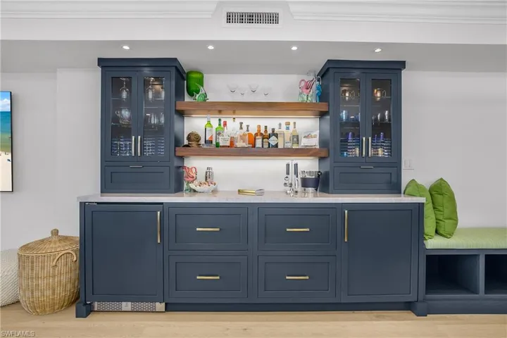 Indoor dry bar featuring a wine cooler, open shelves, glass insert cabinets, and recessed lighting