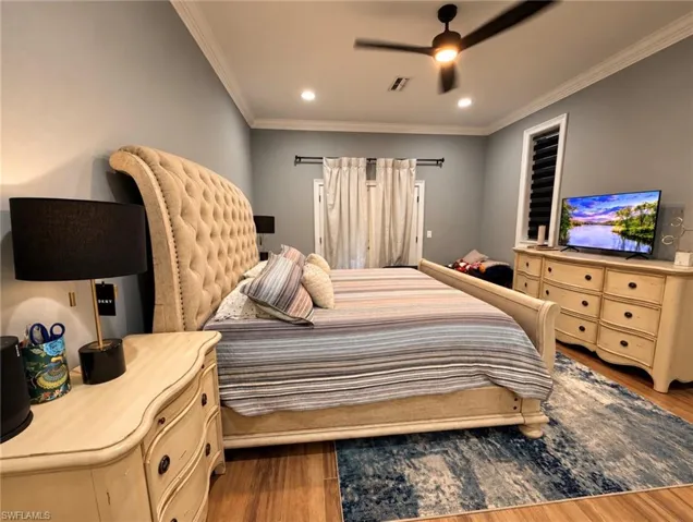 Spacious room featuring crown molding, recessed lighting, wood-finish flooring, a ceiling fan, and double-door access