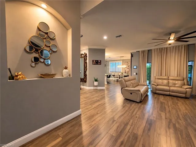 Arched display niche with recessed lighting, wood-finish flooring, and ceiling fan with integrated lighting