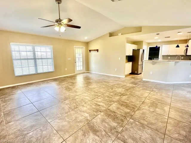 Unfurnished living room with lofted ceiling, a ceiling fan, light tile patterned floors, and recessed lighting